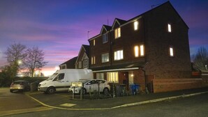 Un edificio residencial de dos pisos con entrada para vehículos y automóviles estacionados.