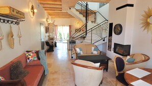 Un salón amplio con una escalera, un sofá, una mesa de comedor y una televisión.