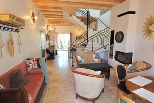 Un salón amplio con una escalera, un sofá, una mesa de comedor y una televisión.