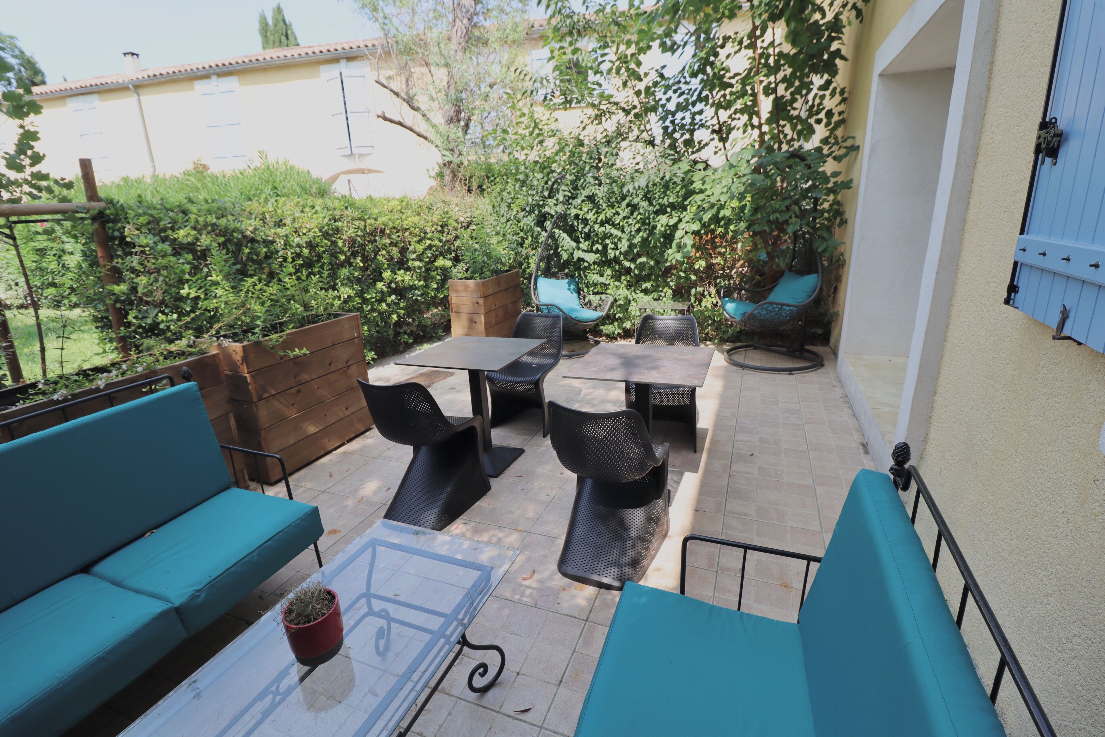An outdoor patio with a table and chairs, a sofa, and a potted plant.