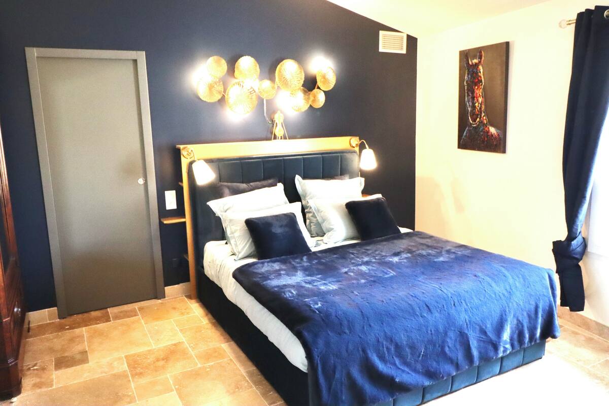 A bedroom with a bed, a headboard, a wall-mounted light fixture, and a door.