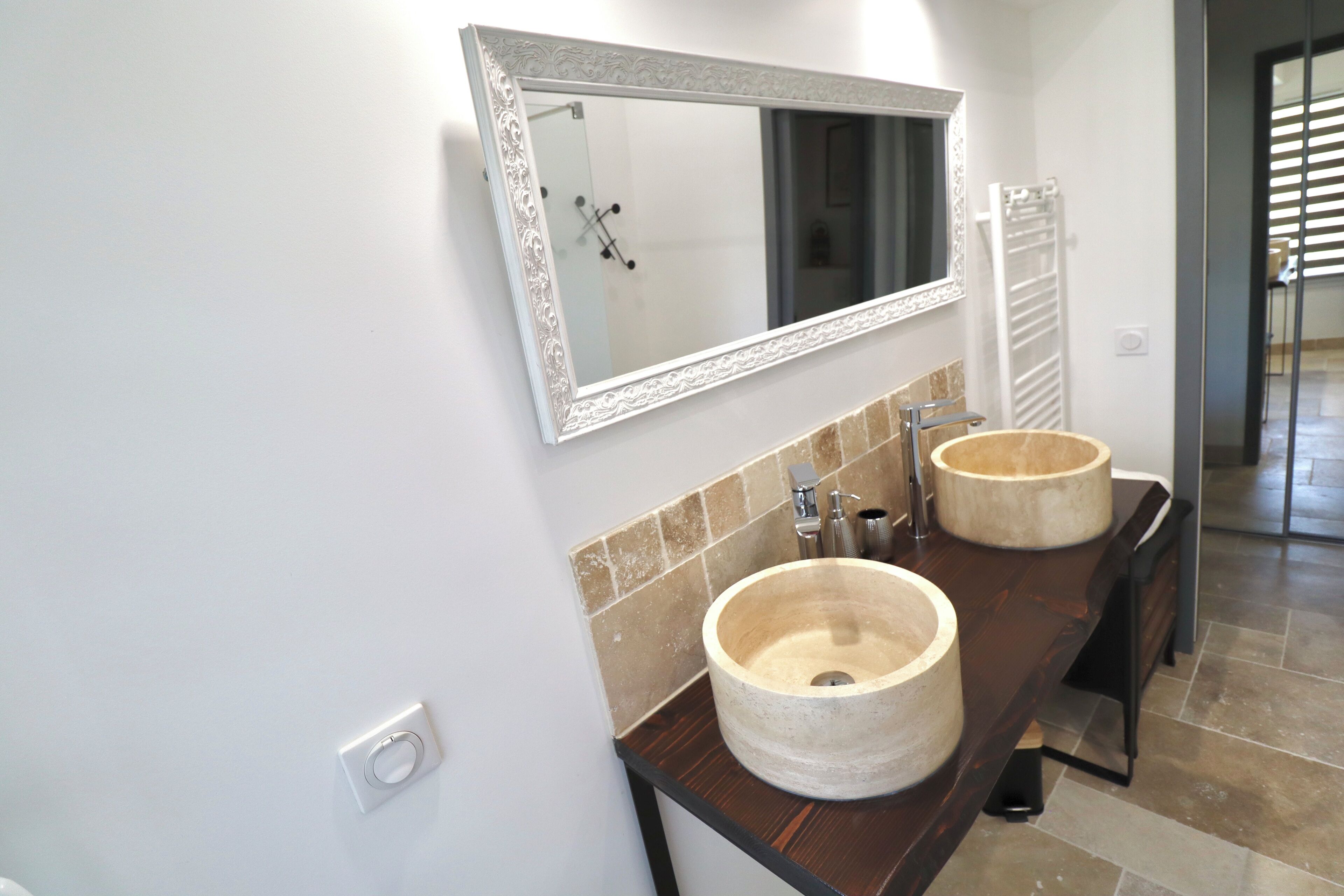 A bathroom with two large, round, beige sinks and a mirror with an ornate frame.