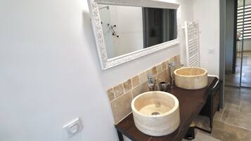 A bathroom with two large, round, beige sinks and a mirror with an ornate frame.