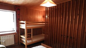 Habitació amb parets de fusta, un lliter superposat, una finestra i un radiador.