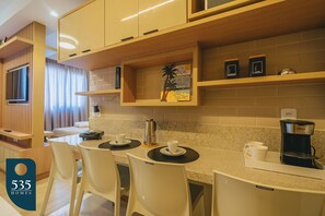 Een koelkast, een magnetron, een blender, kookgerei, borden en bestek