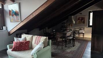 Una sala de estar acogedora con techo alto, un comedor con mesa y sillas, y una escalera que lleva a un nivel superior.