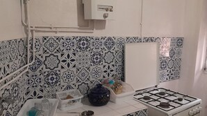 Una cocina con baldosas estampadas, una estufa a gas y un lavamanos.