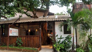 Um edifício rústico com telhado de telhas, cerca de madeira e uma placa.