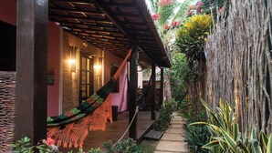 Escadaria de madeira leva a uma área coberta com uma rede e um caminho rodeado por plantas.