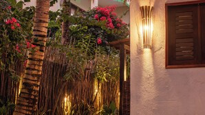 Uma passagem que leva a um edifício com telhado em telhas e uma luminária na parede.