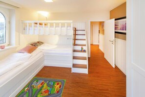 A bedroom with a bunk bed, a window, a wooden floor, and a hallway leading to another room. - Beach Villa Marina 02 beach chair by the sea (Wangerooge)