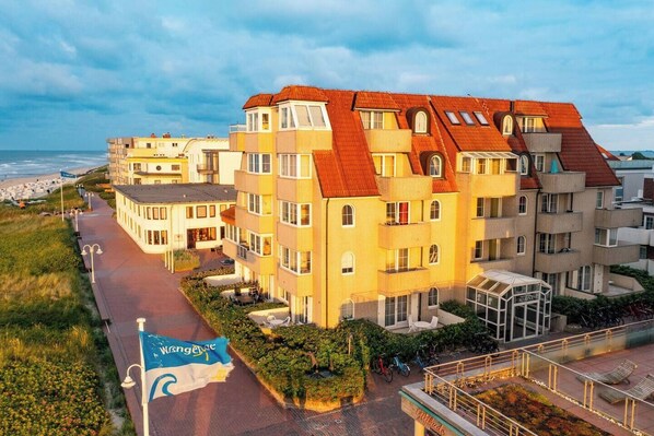A multi-story hotel with a red roof, located near a beach. - Beach Villa Marina 02 beach chair by the sea (Wangerooge)