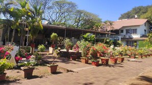 A garden area with potted plants and a covered structure. - Green Hills Resort (Vasai)