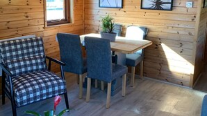 A cozy cabin interior with wooden walls, a dining table with chairs, a checkered sofa, and two framed artworks. - Ant River Lodge Houseboat (Low Street)