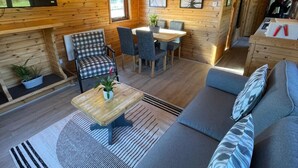 A cozy cabin interior with a sofa, chairs, a dining table, and a TV. - Ant River Lodge Houseboat (Low Street)