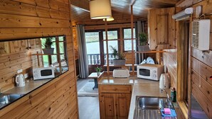 A compact kitchen with wooden walls, a central island, and a stove. - Ant River Lodge Houseboat (Low Street)