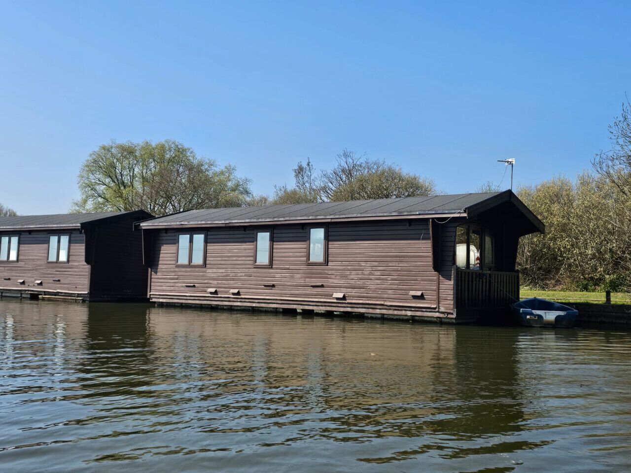 A wooden boathouse with a small dock, situated by a calm body of water.