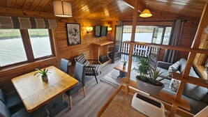 Een chalet met houten inrichting, een eethoek en een zithoek met uitzicht op het water.