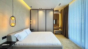 Een moderne hotelkamer met een groot bed, nachtkastjes, een bureau en een groot raam met gordijnen.
