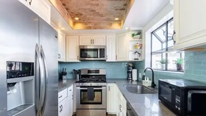Una cocina moderna con electrodomésticos de acero inoxidable, armarios blancos y salpicadero azul.