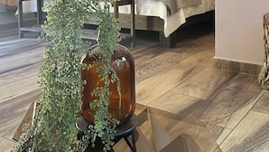 A modern hotel room with a bed, a glass coffee table with a plant, and a hanging light fixture.