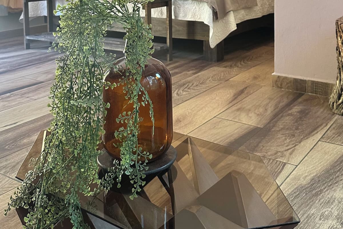 Een moderne hotelkamer met een bed, een glazen bijzettafeltje met een plant en een hanglamp.