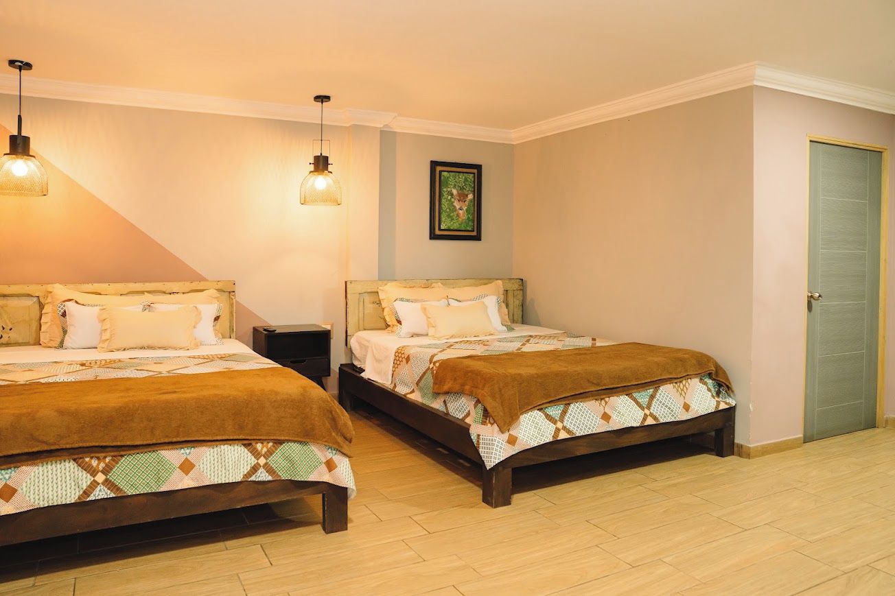 A bedroom with two beds, a nightstand, a framed picture on the wall, and a door.