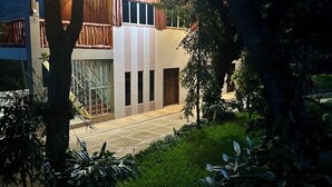 A modern building with a mix of wooden and concrete exterior, surrounded by lush greenery.