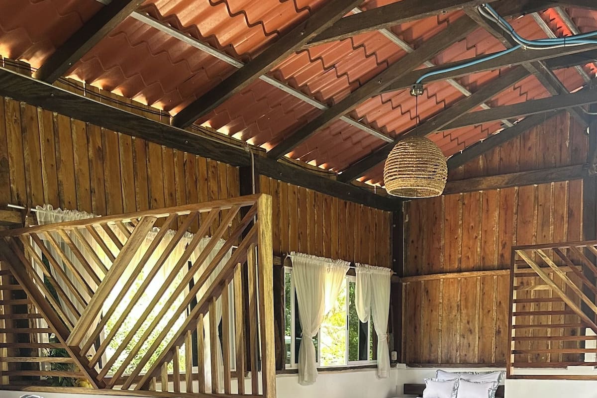 Een kamer met een geruit vloerkleed, houten wanden en twee bedden met beddengoed met een patroon.