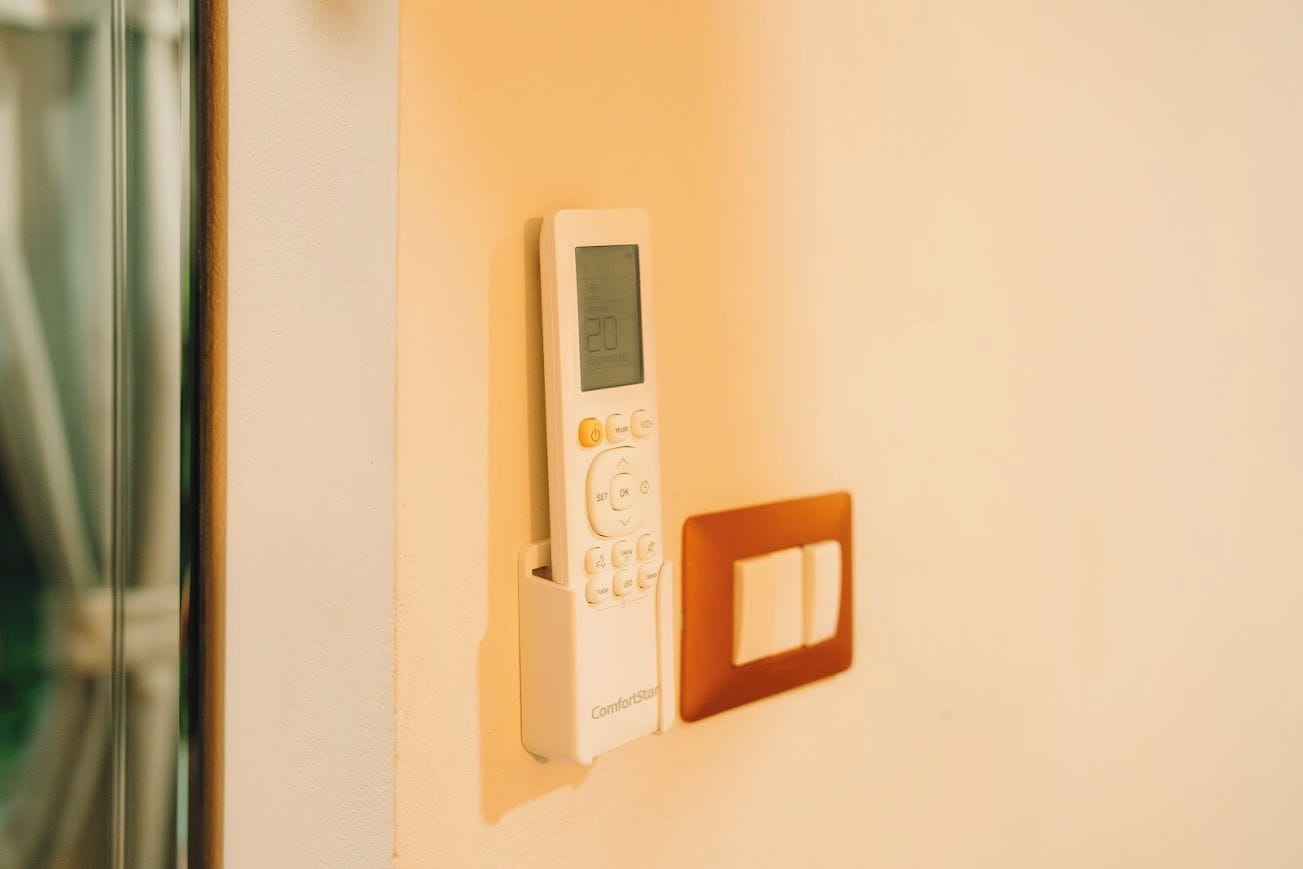 A thermostat with a digital display and control buttons mounted on a wall.