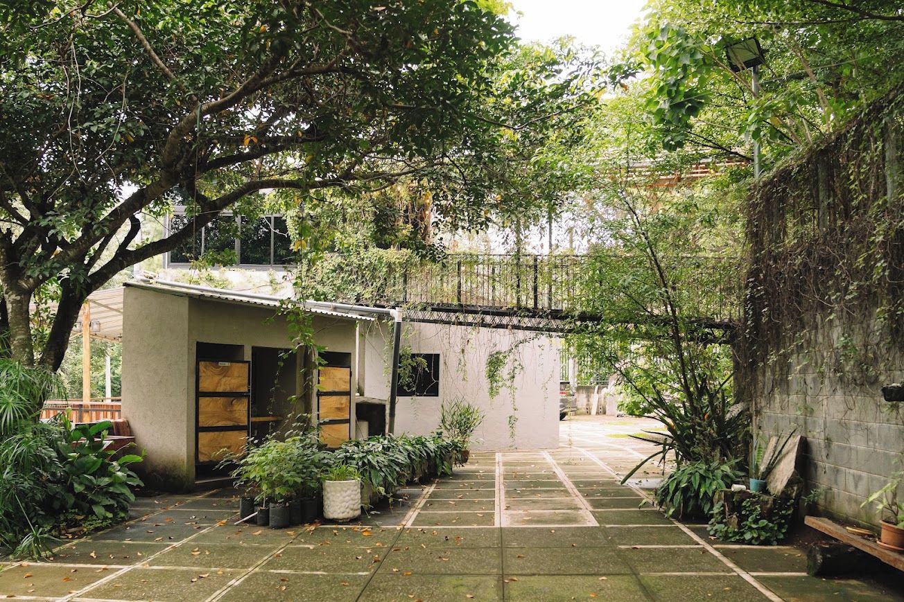 A courtyard with a small building, potted plants, and a covered walkway.