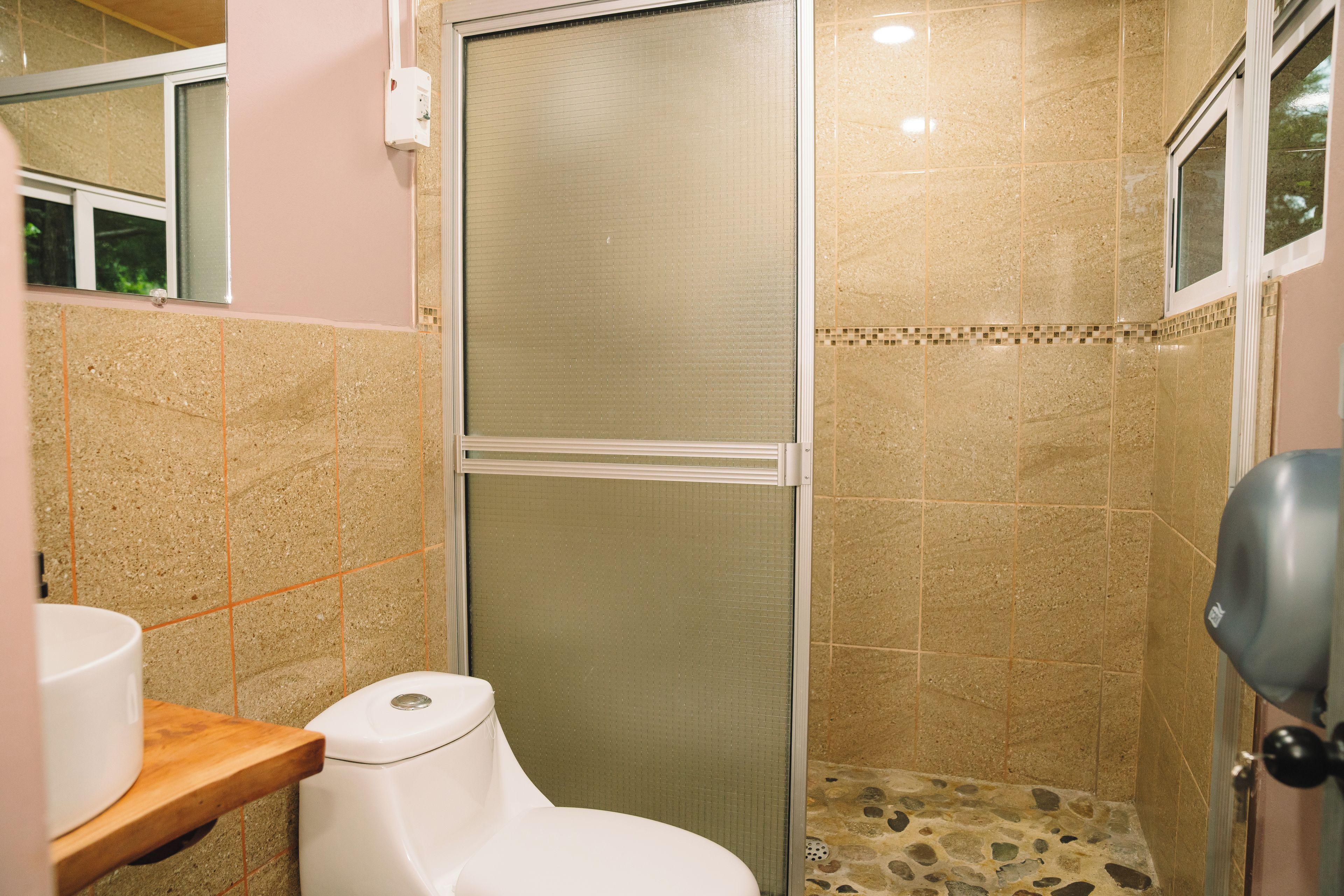 A bathroom with a toilet, a shower stall, and a tiled floor.
