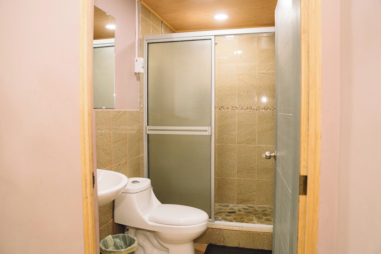 Un baño con inodoro, cabina de ducha y suelo de baldosas.