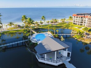 A resort with a pool, lounge chairs, and a view of the ocean.