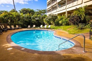 A swimming pool with lounge chairs and a building in the background.