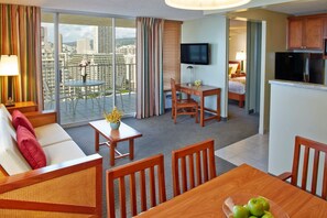 Une chambre d’hôtel avec un balcon, un canapé, une table à manger et un coin cuisine.