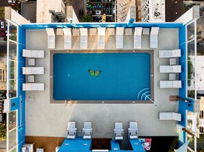 An aerial view of a rooftop pool with a butterfly decoration, surrounded by lounge chairs and a blue pool deck. - Ocean View•1 BR Corner Condo•Mins to Waikiki Beach (Honolulu)
