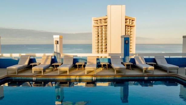 A poolside area with lounge chairs and a view of the sea.