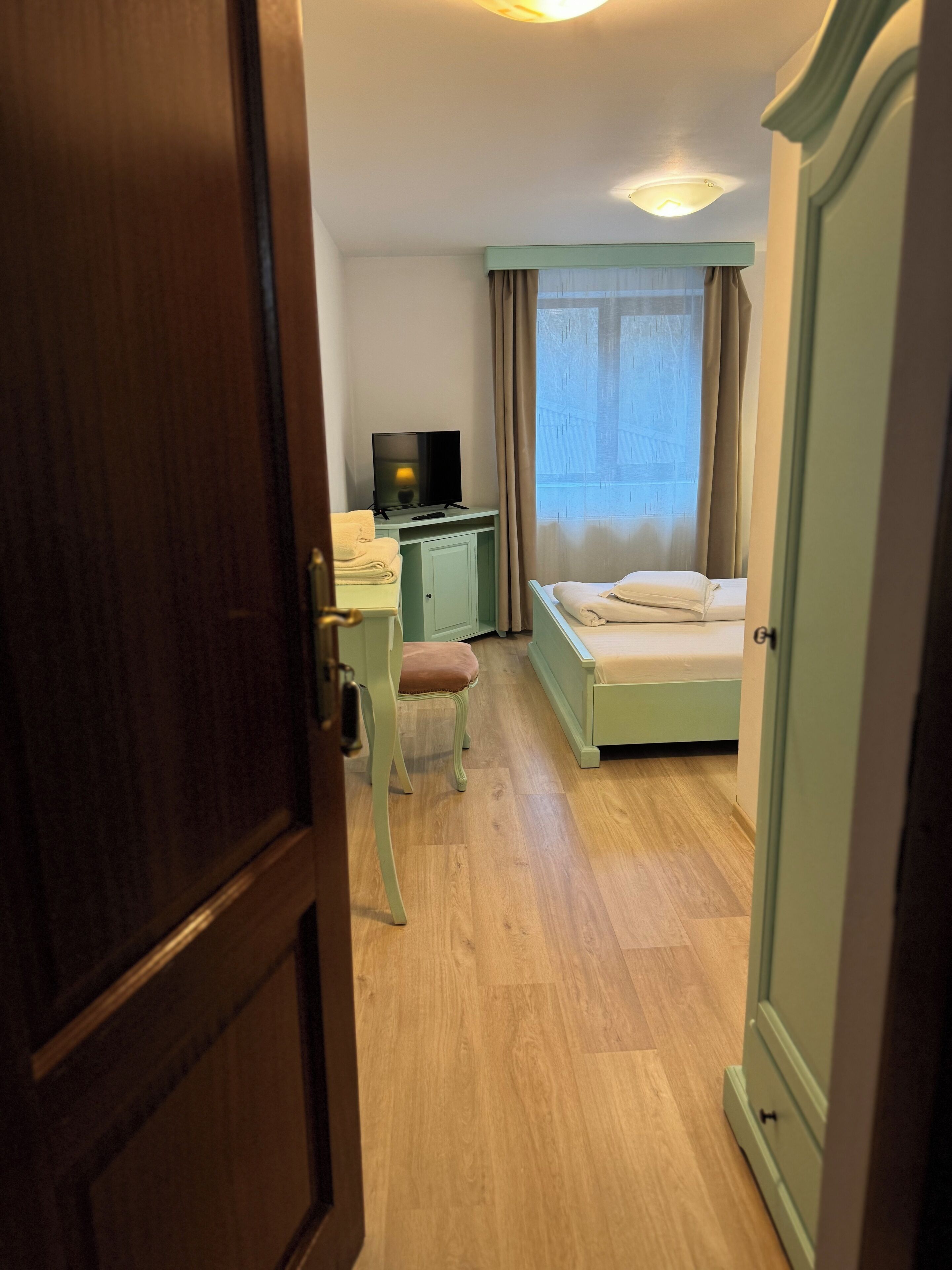 Een hotelkamer met een bed, een bureau met een televisie, een stoel en een kledingkast.