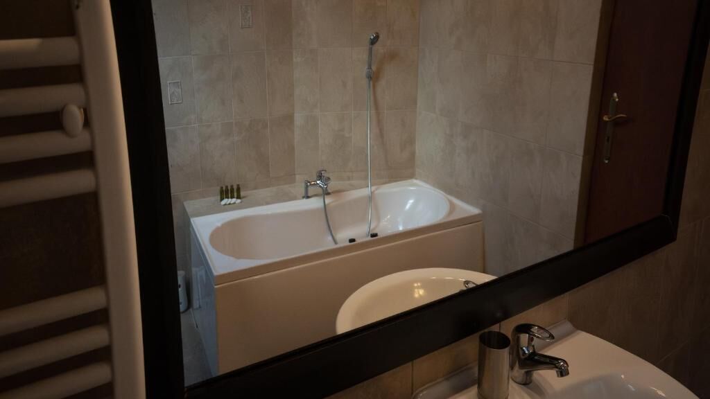 Un baño con bañera, lavabo y espejo que refleja la habitación.