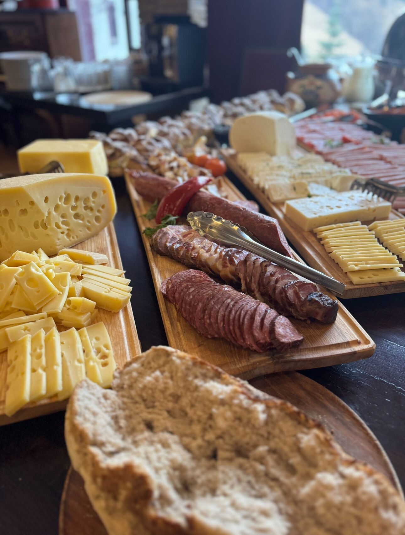 Diversos queijos, carnes e pão em tábuas de madeira.