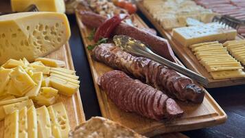 Diversos queijos, carnes e pão em tábuas de madeira.