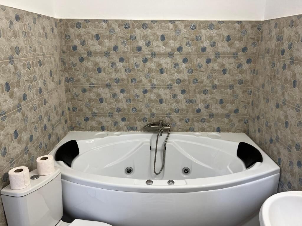 Un baño con una bañera grande, dos rollos de papel higiénico y un inodoro.