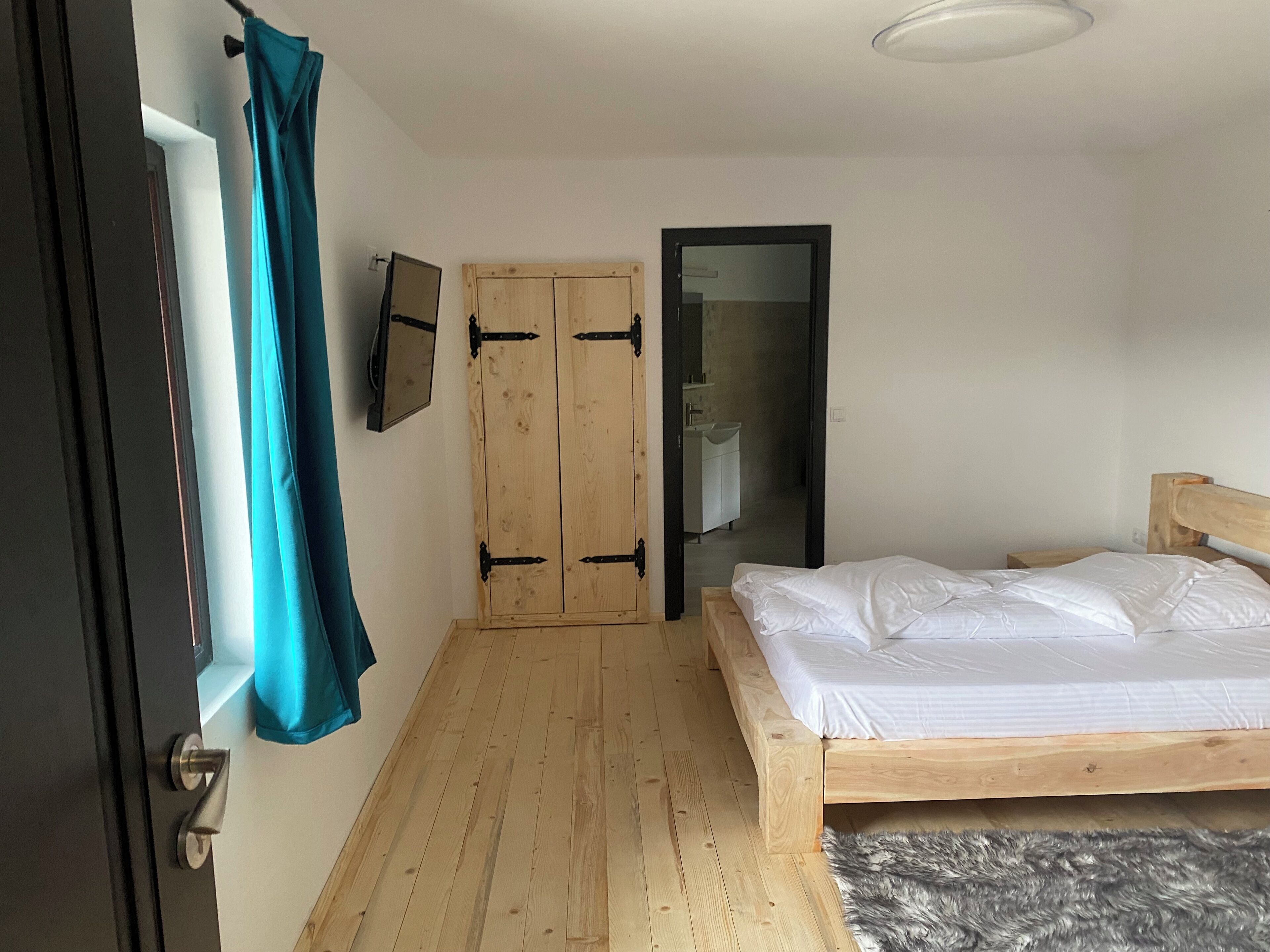 Un dormitorio con una cama de madera, un armario, un espejo y una puerta.