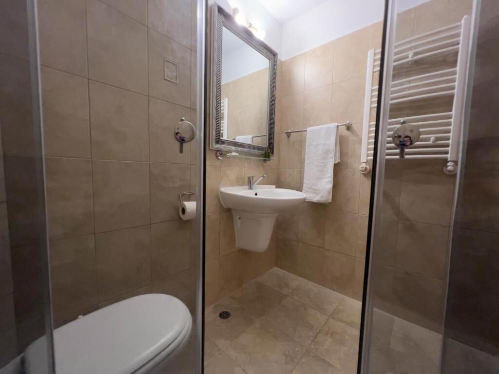 Et badeværelse med toilet, håndvask og brusekabine med glasvægge.