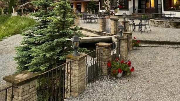 Eine zweistöckige Chalet mit Natursteinfassade, mehreren Balkonen und einer Terrassenanlage mit Gartenmöbeln.