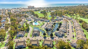 A residential area with houses, a golf course, and a body of water.
