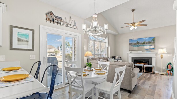 A spacious living room with a fireplace, a dining area with a round table, and a kitchen area.