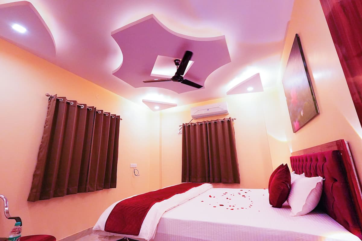 A hotel room with a bed, curtains, a ceiling fan, and an air conditioning unit.