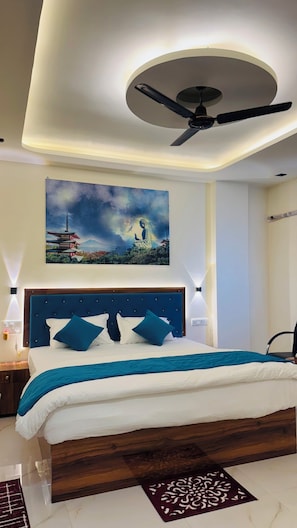 A modern bedroom with a bed, a ceiling fan, a wall-mounted artwork, and a nightstand with a lamp.